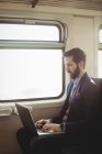 Бизнесмен использует ноутбук во время поездки на поезде — стоковое фото