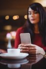 Mujer usando teléfono móvil en restaurante - foto de stock