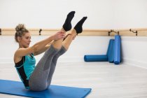Жінка виконує розтяжку вправи в спортзалі на килимку — стокове фото