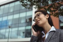 Бізнес-леді розмовляє по мобільному телефону, стоячи на міській вулиці — стокове фото