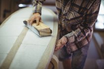 Mid-section of man using sanding block in the surfboard workshop — Stock Photo