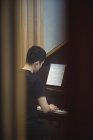 Vista trasera del hombre tocando un piano en un estudio de música - foto de stock