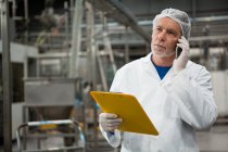 Серйозний чоловік-працівник розмовляє на мобільному телефоні на заводі холодного напою — стокове фото