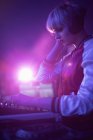 Weiblicher DJ hört Kopfhörer, während er in der Bar Musik abspielt — Stockfoto