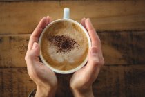 Крупним планом жінка тримає чашку кави в кафе — стокове фото