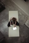 Высокий угол обзора здоровой женщины с помощью мобильного телефона и цифрового планшета на тренировочном коврике дома — стоковое фото