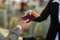 Pasaporte de la compañía aérea que entrega el pasaporte al viajero en el mostrador de la terminal del aeropuerto - foto de stock