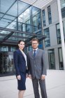 Portrait of confident businessman with colleague standing outside office building — Stock Photo