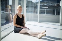 Ballerine assise contre une fenêtre en verre dans le studio — Photo de stock