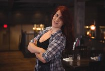 Retrato de uma bela mulher sorrindo com os braços dobrados no bar — Fotografia de Stock