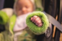 Close-up of baby hand in green baby clothing indoors — Stock Photo