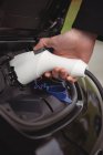 Человек заряжает электромобиль на электростанции зарядки автомобиля — стоковое фото