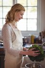 Schöne Frau wäscht Brokkoli unter der Spüle in der Küche zu Hause — Stockfoto