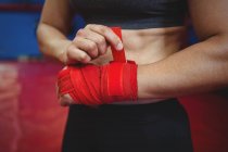 Mid section of female boxer wearing red strap on wrist in fitness studio — Stock Photo