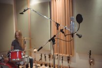 Microfone em estúdio de gravação com músico feminino no fundo — Fotografia de Stock
