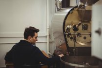 Чоловік сидить поряд з кавоваркою в кав'ярні — стокове фото