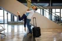 Счастливая пара обнимает друг друга в аэропорту — стоковое фото