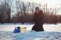 Pescatore di ghiaccio pesca nel paesaggio innevato e alberi — Foto stock