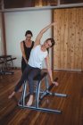 Trainer helping woman while practicing pilates in fitness studio — Stock Photo