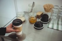 Рука держит чашку кофе на стальном столе в кофейне — стоковое фото