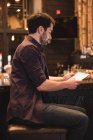 Красивый человек сидит за барной стойкой и использует цифровой планшет — стоковое фото