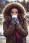 Portrait of beautiful woman in fur coat drinking coffee in winter — Stock Photo