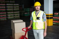 Young male worker pulling trolley in warehouse — Stock Photo
