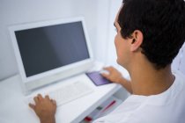 Rear view of dentist using computer at clinic — Stock Photo