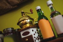Close-up of coffee grinder and syrup bottles arranged on shelf in shop — Stock Photo