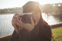 Mujer tomando fotos en cámara digital en un día soleado en el parque - foto de stock