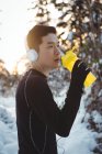 Вдумчивый человек пьет воду, слушая музыку в наушниках — стоковое фото