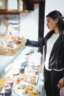 Frau wählt verpackte Snacks an Lebensmitteltheke im Supermarkt aus — Stockfoto