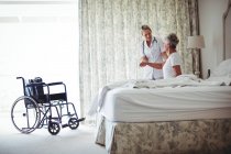 Жінка-лікар консультує старшого пацієнта в спальні — стокове фото