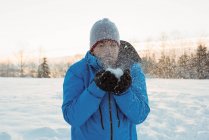 Чоловік дме сніг і насолоджується сонячним зимовим днем — стокове фото