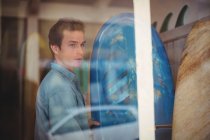 Man selecting blue surfboard in a shop — Stock Photo