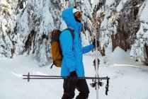 Vista laterale dello sciatore che cammina con sci sulle montagne innevate — Foto stock