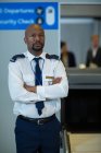 Portrait of airport security officer standing with arms crossed in airport terminal — Stock Photo