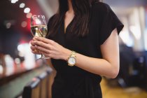 Средняя секция женщины, держащей бокал вина в ресторане — стоковое фото