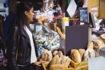Mujer de pie en el mostrador de pan en el supermercado - foto de stock