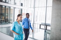 Médico y enfermera caminando en pasillo en el hospital - foto de stock