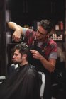 Man getting hair trimmed by hairdresser with scissors in barber shop — Stock Photo