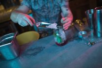 Бармен кладет лёд в банку во время приготовления коктейля в баре — стоковое фото