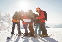 Grupo de esquiadores mirando el mapa en los Alpes nevados durante el invierno - foto de stock