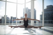 Балерина делает упражнения на растяжку в балетной студии — стоковое фото