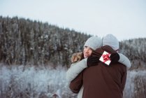 Happy couple embracing each other on snow covered mountain — Stock Photo