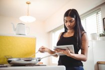 Frau kocht und nutzt digitales Tablet in der Küche — Stockfoto