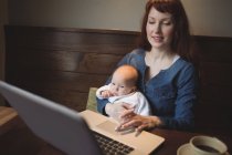 Madre con bambino usando il computer portatile nel caffè — Foto stock