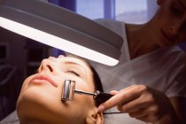 Жіночий дерматолог, що проводить лазерну епіляцію на обличчі пацієнта в клініці — стокове фото