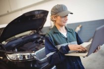 Женщина-механик с ноутбуком в ремонтном гараже — стоковое фото