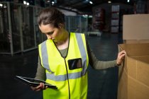 Serious female worker using tablet pc in warehouse — Stock Photo